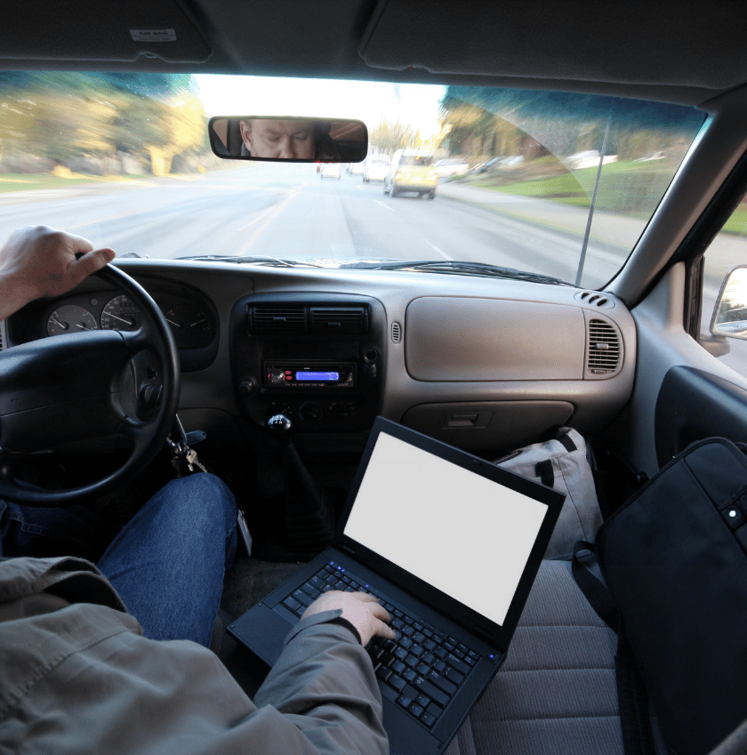 male typing a laptop while driving another distracted driving